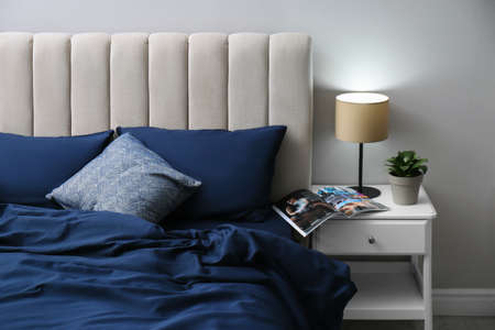 Bed with stylish silky linens in roomの写真素材