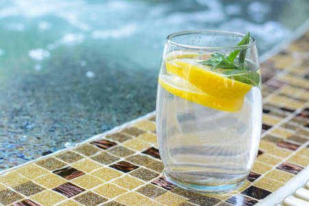 Refreshing water with lemon and mint on edge of swimming pool, space for textの写真素材