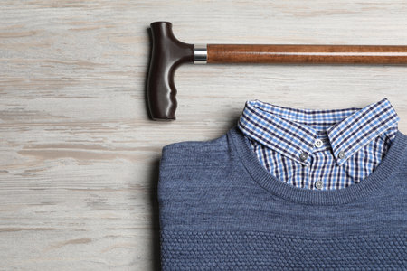 Elegant walking cane and sweater on light wooden table, flat layの写真素材