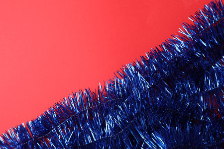 Bright blue tinsel on red background, top view. Space for textの写真素材