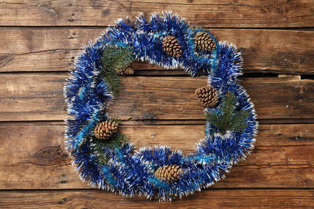 Frame of bright tinsel, fir tree branches and pine cones on wooden background, top view with space for text. christmas decorの写真素材