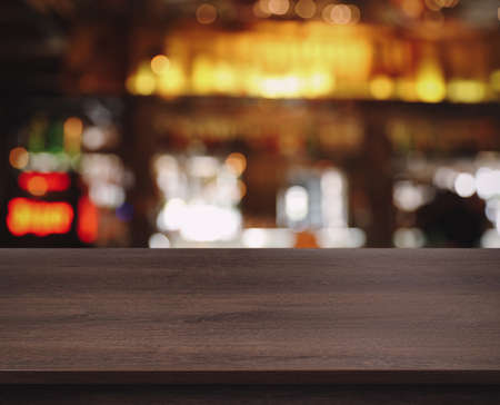 Empty wooden surface and blurred view of bar interior. space for design