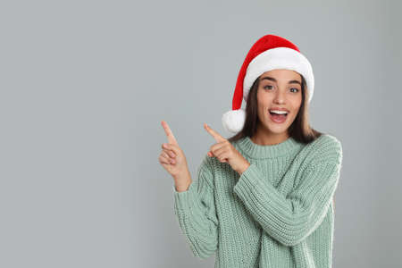 Happy woman in Santa hat on gray background, space for text. christmas count down