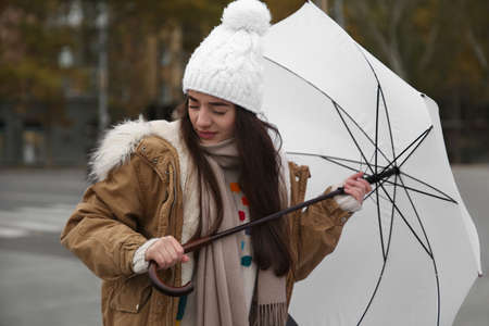 Woman with white umbrella caught in gust of wind on streetの写真素材