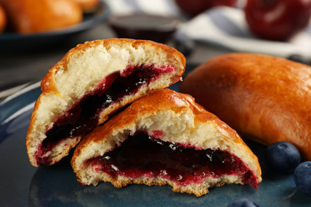 Delicious baked patties with jam and blueberries on plate, closeup
