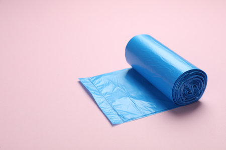 Roll of light blue garbage bags on pink background. Space for textの写真素材