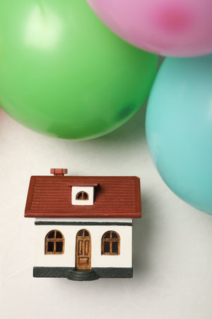 Wooden house model and balloons on white table, flat lay. house warming partyの写真素材