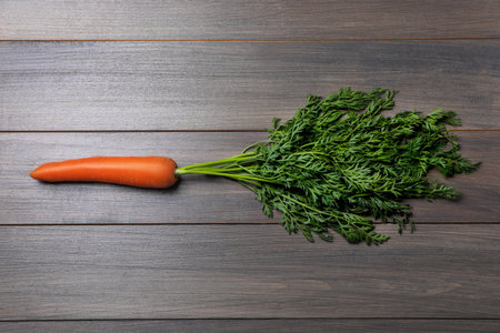 Tasty ripe carrot on wooden table, top view
