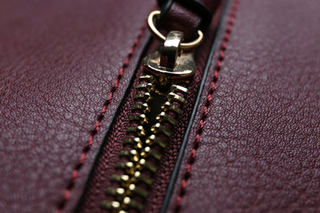 Burgundy leather fabric with zipper as background, closeup