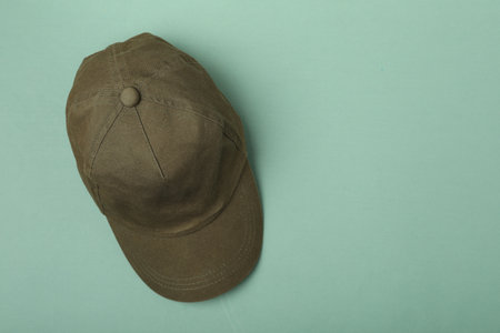 Baseball cap on light green background, top view. Space for text