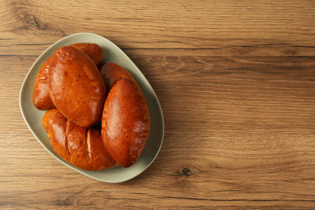 Delicious baked pirozhki on wooden table, top view. Space for textの写真素材