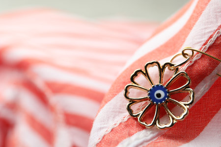 Evil eye safety pin on clothing, closeup