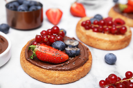 Tasty organic rusks with different toppings and ingredients on white table, closeupの写真素材