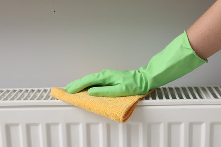 Woman cleaning radiator with rag indoors, closeupの写真素材