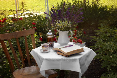 Beautiful bouquet of wildflowers and books on table served for tea drinking in gardenの写真素材