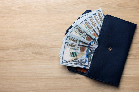 Dollar banknotes in wallet on wooden table, top view with space for text. money exchange