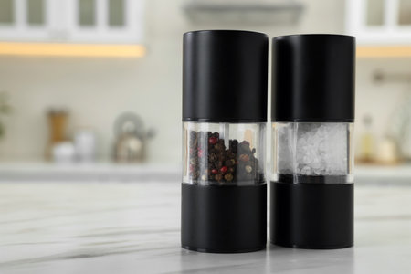 Salt and pepper mills on white marble table in kitchen. Space for textの写真素材