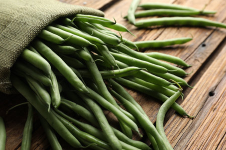 Fresh green beans in bag on wooden table, closeup