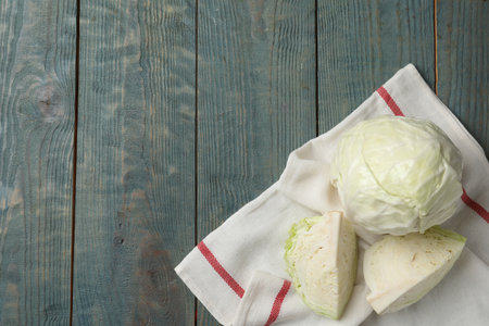 Fresh whole and cut cabbages on blue wooden table, flat layの写真素材