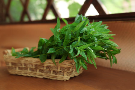 Beautiful green mint in wicker basket on wooden table