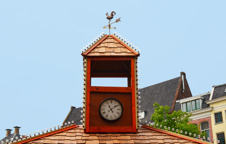 Tower with clock and weather vane on roof of old buildingの写真素材