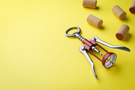 Corkscrew and wine bottle stoppers on yellow background. Space for text