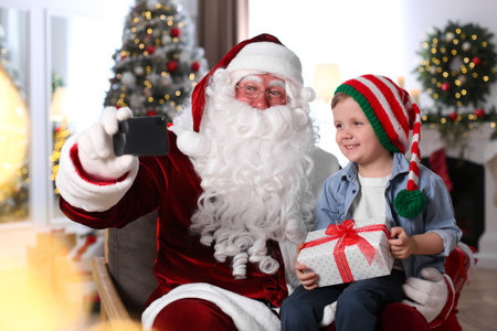 Santa Claus and little boy taking selfie in room decorated for Christmasの写真素材