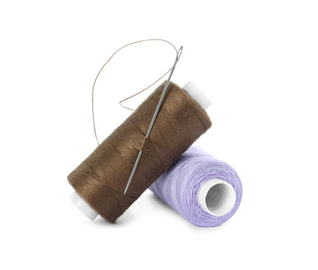 Different colorful sewing threads and needles on white background