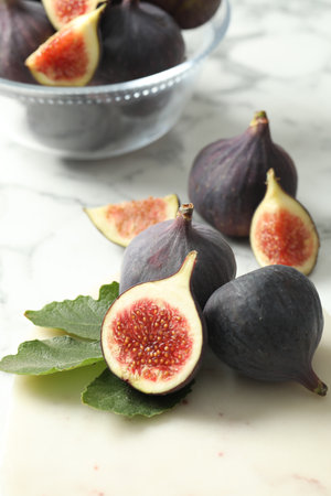 Whole and cut tasty fresh figs on white marble tableの写真素材