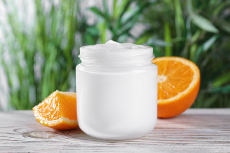 Jar of hand cream and orange on white wooden tableの写真素材