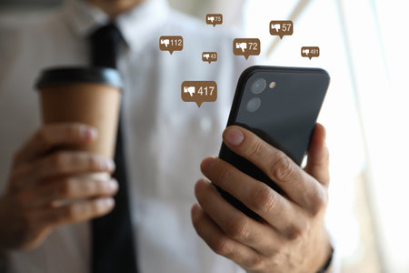 Closeup view of young man using modern smartphone indoors and virtual dislike icons. Cyberbullying...