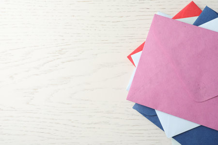 Colorful paper envelopes on white wooden background, top view. Space for textの写真素材
