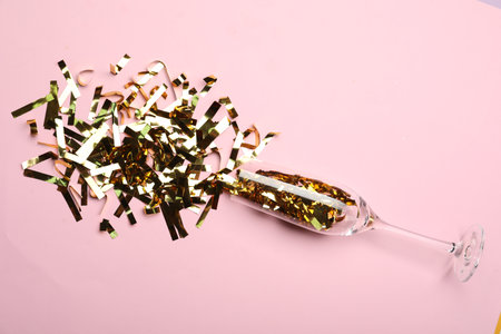 Glass and shiny confetti on pink background, flat layの写真素材
