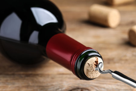 Opening wine bottle with corkscrew on wooden table, closeupの写真素材