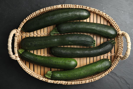 Basket with green zucchinis on black slate table, top viewの写真素材