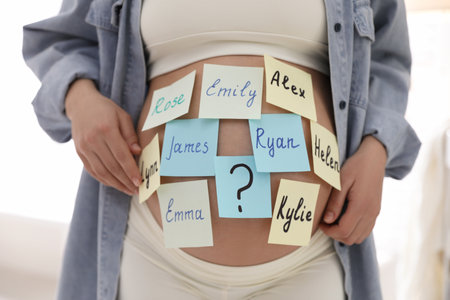 Pregnant woman with different baby names on belly indoors, closeupの写真素材
