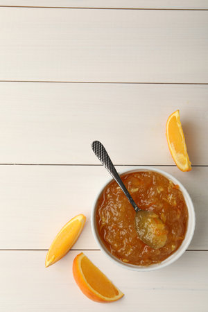 Delicious orange marmalade and fruit slices on white wooden table, flat lay. Space for textの写真素材