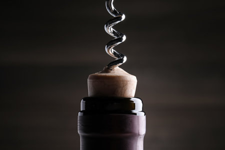 Opening wine bottle with corkscrew on dark background, closeupの写真素材