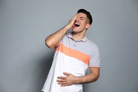 Handsome man laughing on gray background. funny jokeの写真素材