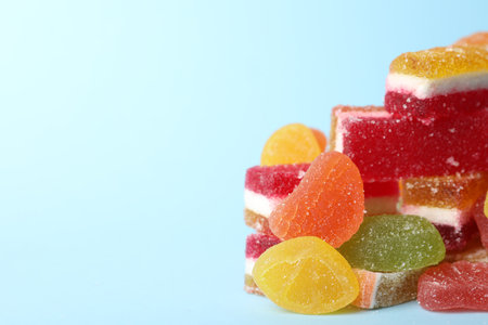 Pile of delicious bright jelly candies on light blue background, closeup. Space for textの写真素材