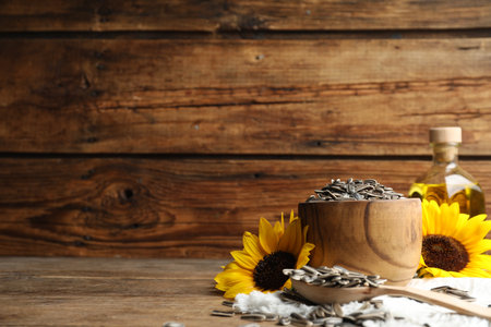 Organic sunflower seeds and flowers on wooden table. Space for textの写真素材