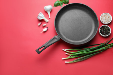 Flat lay composition with frying pan and fresh products on red background, space for textの写真素材