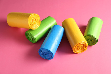 Rolls of different garbage bags on pink backgroundの写真素材