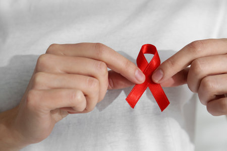 Woman holding red awareness ribbon, closeup. World AIDS disease day