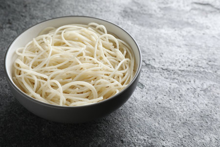Bowl of tasty cooked rice noodles on gray table. Space for textの写真素材