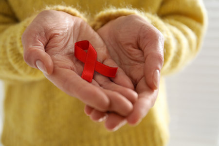 Woman holding red awareness ribbon on light background, closeup. World AIDS disease dayの写真素材