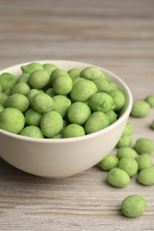 Bowl with tasty wasabi coated peanuts on white wooden table, closeupの写真素材