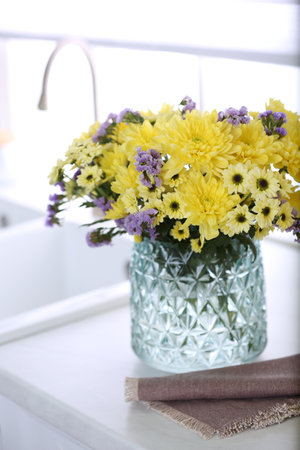 Vase with beautiful chrysanthemum flowers on countertop in kitchen. interior designの写真素材