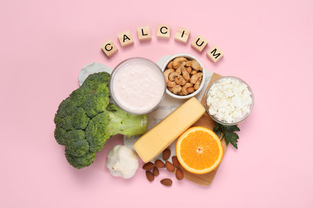 Food high in calcium. Different products and wooden cubes on pink background, flat layの写真素材