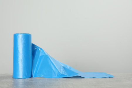 Roll of color garbage bags on table against light background. Space for textの写真素材